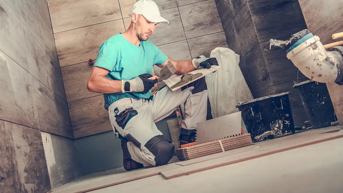 Ein Fliesenleger bei der Arbeit in einem Badezimmer