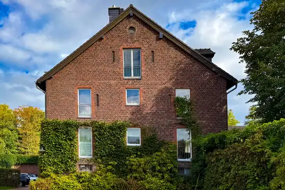 Hauswand Backsteingebäude mit ordentlich zurückgeschnittenem Weinbewuchs nach dem Rückschnitt durch raumgut Immobilien